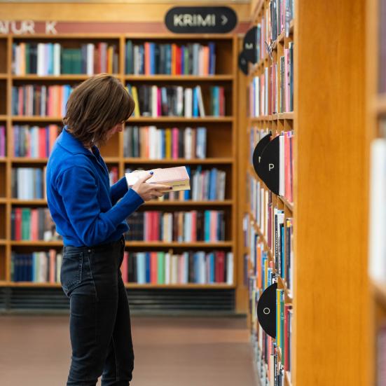 Låner kigger i en bog blandt reolerne