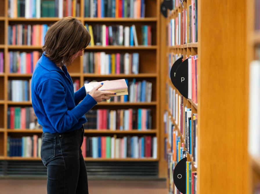 Låner kigger i en bog blandt reolerne